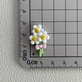 Vue macro d'une fleur marguerite en résine avec nœud rose sur tapis de mesure de 3 cm - 04*Trois fleurs souriantes