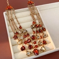 Detailweergave van een vintage meerlagige ketting met oranje stenen in een beige sieradendoos - Gelaagde ketting / Ketting-Goud-Bruin