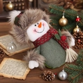 Christmas snowman doll with green body and fur hat on a rustic wooden holiday tabletop - Snowman