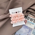 Three-piece set of light pink satin scrunchies with a smooth silky finish on a card - Pink