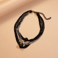 Detailaufnahme mehrlagiger Metallketten in Schwarz und Silber mit Perlenanhänger - Schwarz
