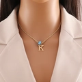 Close-up of gold letter K pendant and blue evil eye bead on a rope chain necklace - Letter K (N1339)