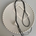 Détail macro du pendentif triangulaire géométrique sur collier en cuir noir minimaliste - Collier-Noir-Argent / Argenté