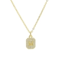 Macro shot of gold square pendant with letter M and cubic zirconia on thin chain - Necklace M