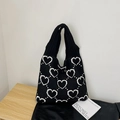 Chic black knitted tote bag featuring white heart patterns on a wooden surface - Black