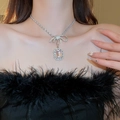Close-up of sparkling rhinestone bow and square pendant necklace on model neck - Style 19 Necklace