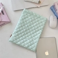 Detail of mint green quilted laptop sleeve with diamond patterns and woven brand label - Mint Green