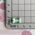 Mini light green resin bone accessory measuring 1.5cm shown on a metric scale grid - Green
