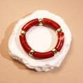Détail de segments en résine marbrée et de perles dorées sur un socle en pierre - Forme de Nœud de Bambou / Rouge