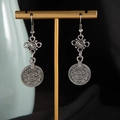 Macro detail of ethnic silver coin tassel earrings hanging on a vintage gold display stand - Antique Silver Earrings (S3340-2)