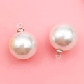 Set of two round white pearl pendants with silver metal loops on a pink background - 14mm Silver Round