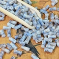 Makroaufnahme von 8mm zylindrischen Keramikperlen mit blau-brauner Glasur auf Vintage-Stoff - Wolkenblau (Bemalt 6x12mm)