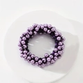 Macro detail of purple pearl hair tie with high elastic black rope on white base - Fuschia