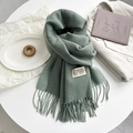 Detail of moss green cashmere scarf featuring decorative long tassels and stitched label - Cyan Green