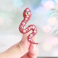 Handheld silver snake brooch adorned with shimmering red crystals and iridescent rhinestones - Red