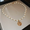 Close-up of pearl necklace with a vintage gold portrait coin pendant and green gemstone - Gold Vintage Portrait Coin Necklace