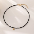 Collana girocollo minimalista con perline nere e un piccolo ciondolo a croce dorato - Pendente a Croce / Perline Sfaccettate Nere / Nero
