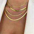 Detail of layered gold snake bone chain necklaces on a model wearing a white suit - Gold 2mm Width 45cm Length