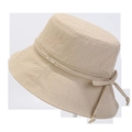Detail eines Sommer-Fischerhuts mit Faltenstruktur und dekorativer Webschleife mit Metall-Anhänger - M (56-58cm) / Beige