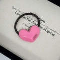 Close-up of pink heart hair tie with France Handmade text on a minimalist canvas background - Pink