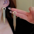Vista macro de pendientes dorados de borla con pedrería en forma de C y cadena de metal - Pendientes de botón de semicírculo con circonita y borla - dorado