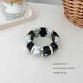 Détail d'un bracelet géométrique rétro en acrylique avec motif marbre et liens dorés - Rayures Noir et Blanc