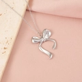 Dettaglio del ciondolo a fiocco in argento lucido su tessuto rosa e marmo chiaro - Stile Fiocco 2 (2#)