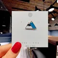 Handheld view of a blue and white snow mountain enamel pin with gold plating on card - 107*Mount Fuji Mountain Pin
