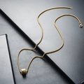 Detail of a minimalist gold cylinder pendant on a box chain with a polished metallic finish - Gold
