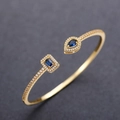 Macro detail of open gold bracelet featuring blue gemstone and micro-inlaid zircon crystals - Gold+Blue Zirconia