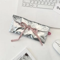 Pochette argentée matelassée avec nœud rose et broderie papillon sur bureau blanc - Style de cravate à rabat matelassé à nœud / Argent