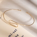 Macro shot of minimalist gold spiral layered bracelet on book pages with soft lighting - Gold Minimalist Paperclip Design Bracelet