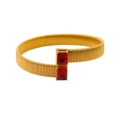 Close-up of golden textured cuff bracelet featuring two rectangular red gemstones - Red