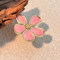 Ring mit rosa Emaille-Blume, Goldrand und Glitzerdetails auf rustikalem Holzständer - Rosa