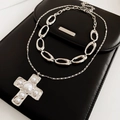 Dettaglio della collana con croce d'argento e perle su una borsa a busta in pelle nera - Set da Due Pezzi (Include Pendente a Croce) / Argento