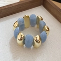 Vista macro detallada de las cuentas de acrílico azul mármol y eslabones dorados de pulsera - Azul