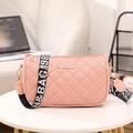 Pink quilted shoulder bag with wide strap and gold logo detail in home setting - Pink