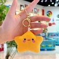 Plush yellow star keychain with smiley face and golden metal clasp held in hand - Orange Star with Gold Clasp