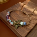 Detail of vintage woven bracelet with ceramic beads and a bronze butterfly charm - Butterfly Ceramic Bead Style