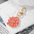 Porte-clés marguerite rose et doré sur une surface en pierre blanche texturée - Rose