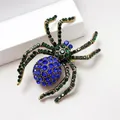 Macro shot of spider brooch with a deep blue crystal and green rhinestone details - Blue