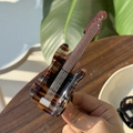 Détail de la pince à cheveux guitare en acétate écailles de tortue avec des reflets brillants - Guitare Écaille