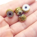 Macro detail of four rotating mantra prayer beads in gold and silver finish on palm - Pixiu / D11.5mmxH9mm