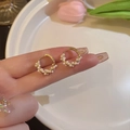 Dettaglio di orecchini a cerchio dorati con piccole perle bianche e stile chic - Torsione di Perle Dorate