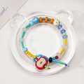 Colorful beaded bracelet with red apple charm on a bear-shaped transparent display tray - Acrylic Bear Display Tray