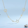 Collana minimalista a stelle in oro e acciaio su sfondo azzurro con foglia secca - Oro