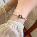 Elegant pearl and colorful stone bracelet with a clover charm on female wrist - Gold/Four-Leaf Clover