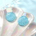 Macro-opname van blauwe glitter schelpen van hars in een parelschaal op watergolven - Hemelsblauw