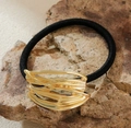 Detail of a wavy gold metal accent on a black elastic hair tie set on a natural stone surface - Style 1-Irregular Wavy