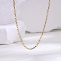 Detalle de un collar de cadena box de acero inoxidable dorado sobre mármol blanco - Dorado